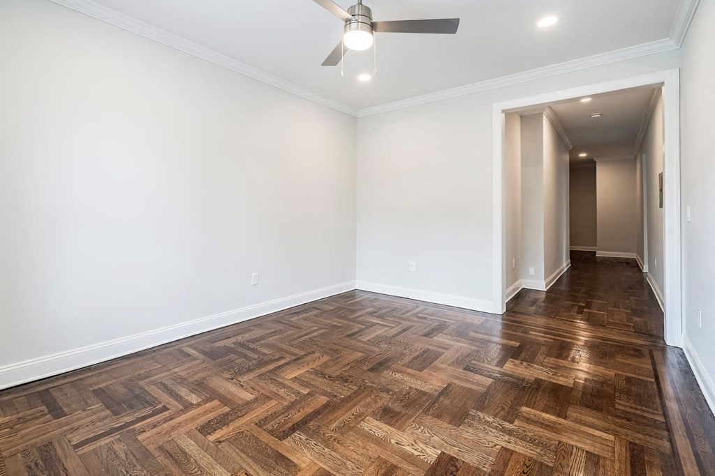 an empty living room with wood flooring and a ceiling fan