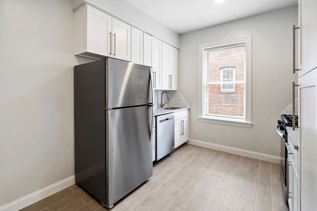 an empty kitchen with a refrigerator and a window