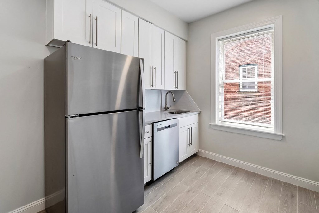 a kitchen with white cabinets and a stainless steel refrigerator
