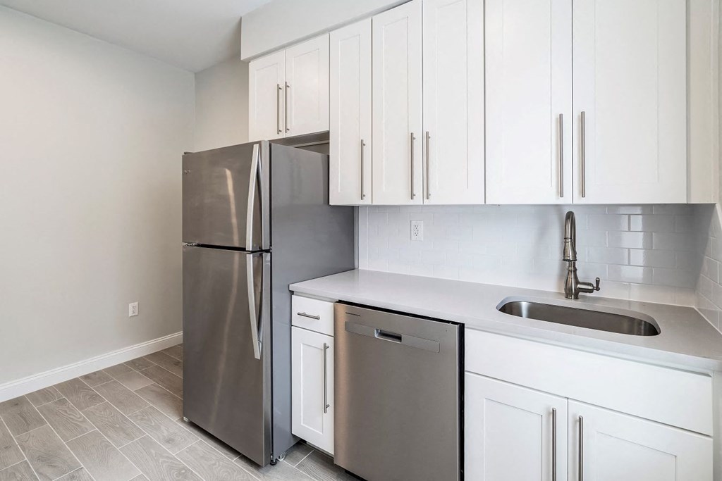 a kitchen with white cabinets and a stainless steel refrigerator