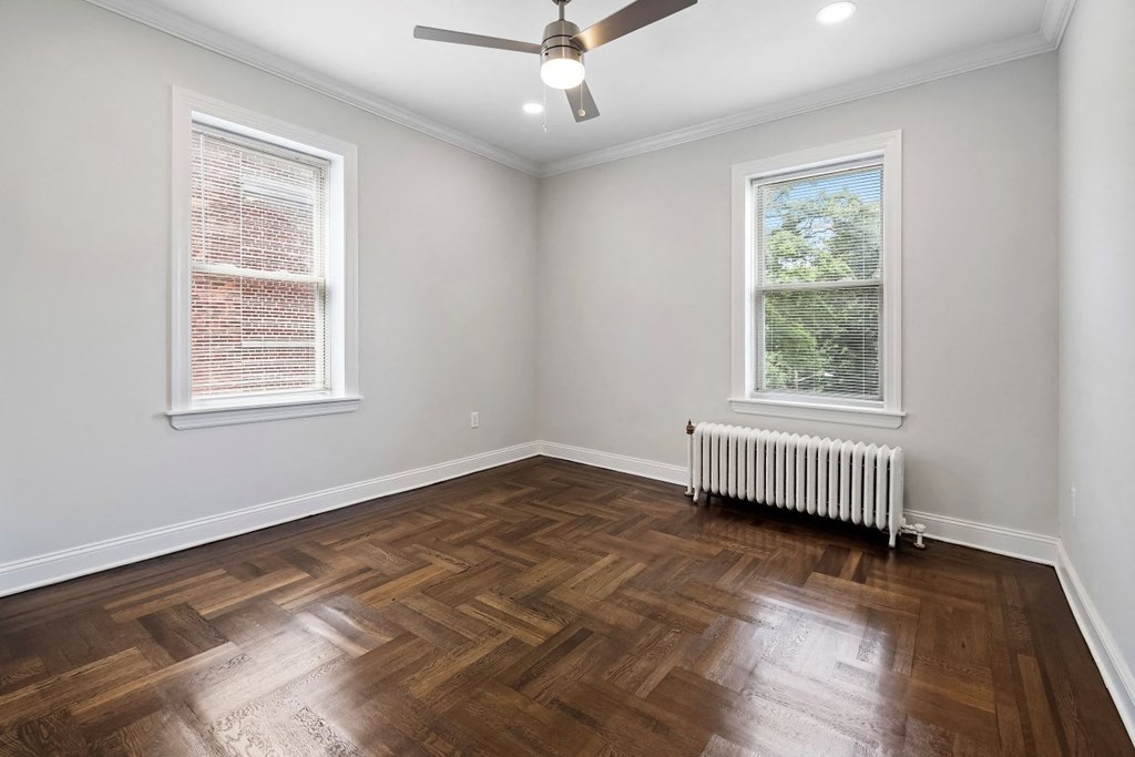 an empty living room with wood floors and a ceiling fan