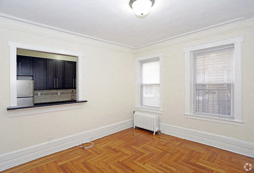an empty living room with a window and a radiator on the floor