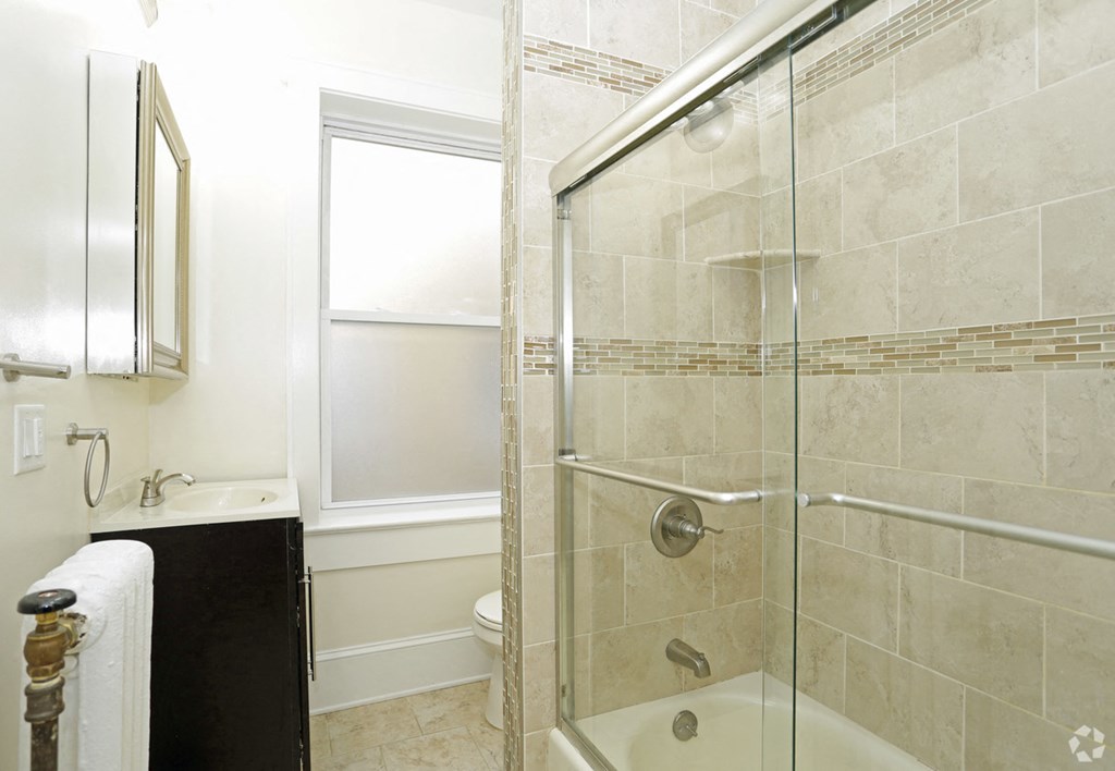 a bathroom with a shower and a sink and a window