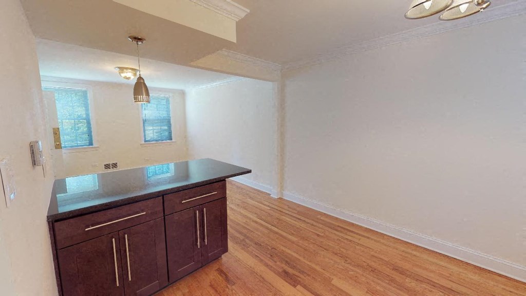 an empty living room with a kitchen with a counter top
