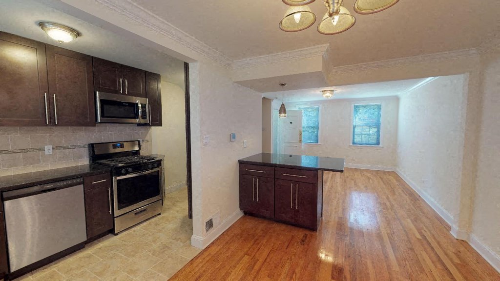 an empty kitchen and living room with wooden floors and stainless steel appliances