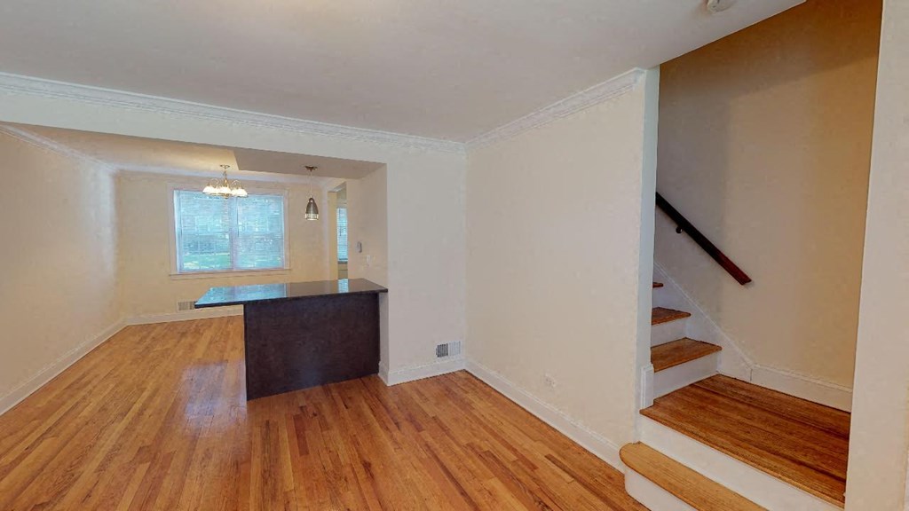 an empty living room with wood floors and a staircase