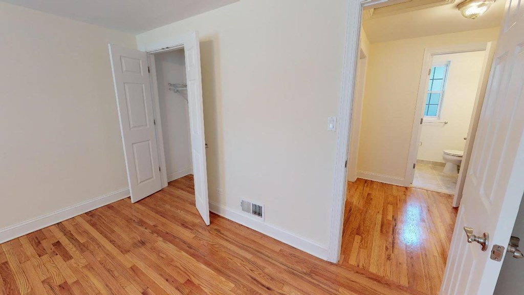 a living room with a wooden floor and a door to a bathroom