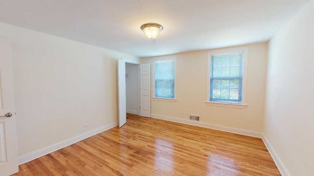 an empty living room with a hard wood floor and a door to a bedroom