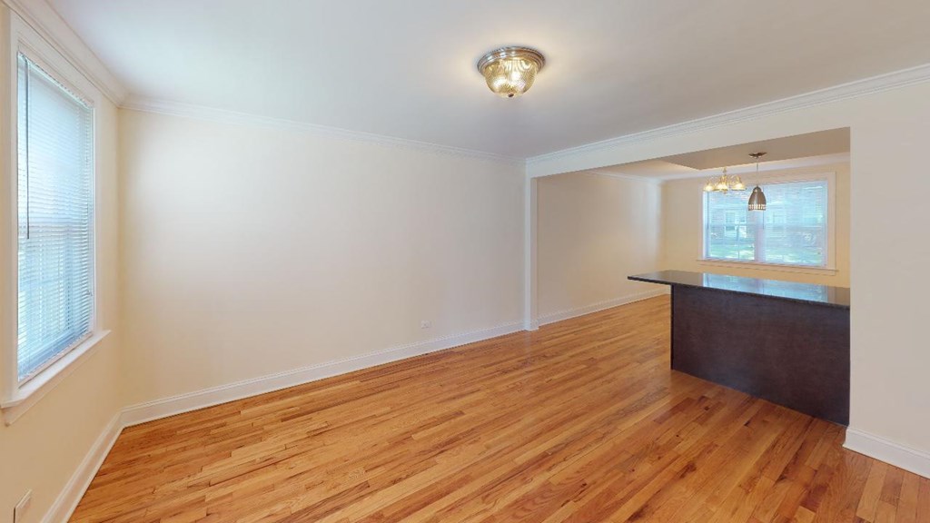 an empty living room with a hard wood floor and a kitchen