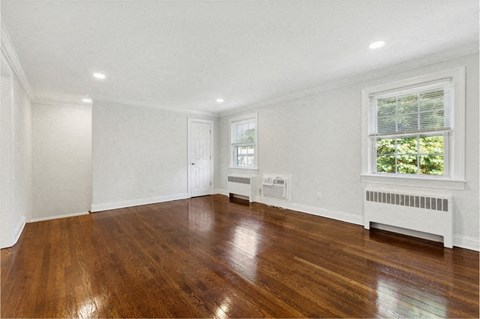 a living room with wood floors and white walls and a window