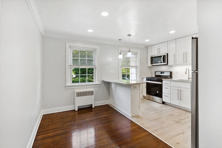 an empty kitchen with white cabinets and a window