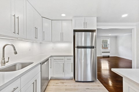 a white kitchen with white cabinets and a stainless steel refrigerator