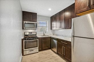an empty kitchen with wooden cabinets and stainless steel appliances