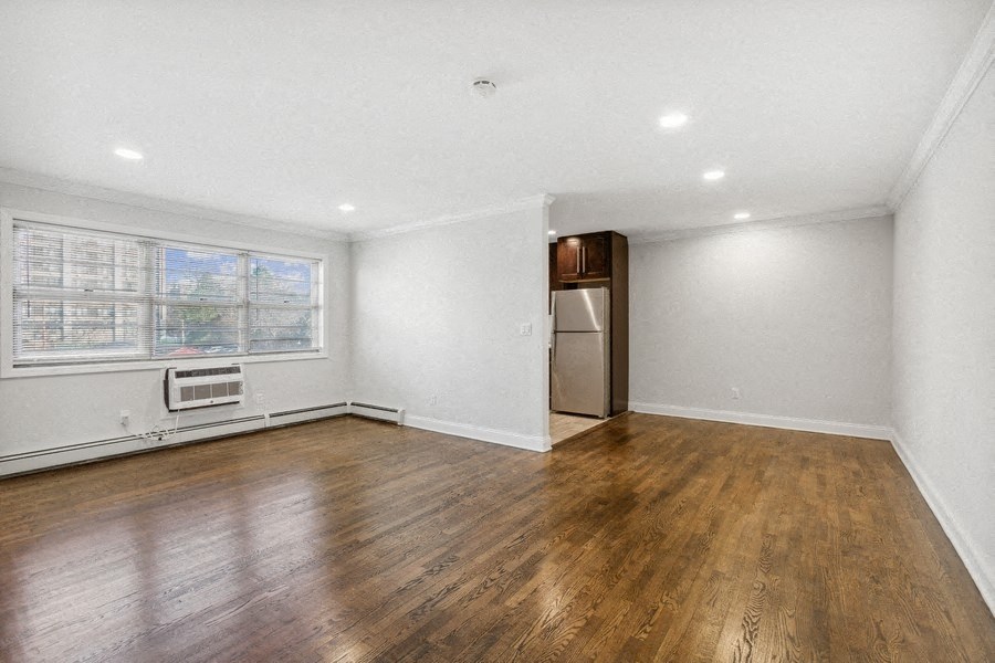 an empty living room with white walls and wooden floors and a window
