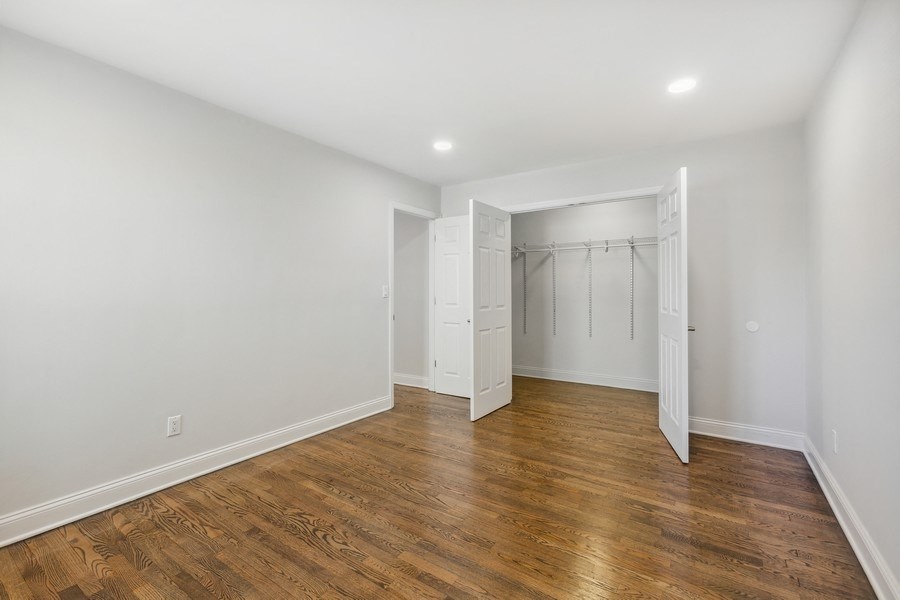 a room with white walls and wood flooring and a closet