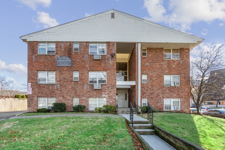 a red brick apartment building with a lawn and stairs