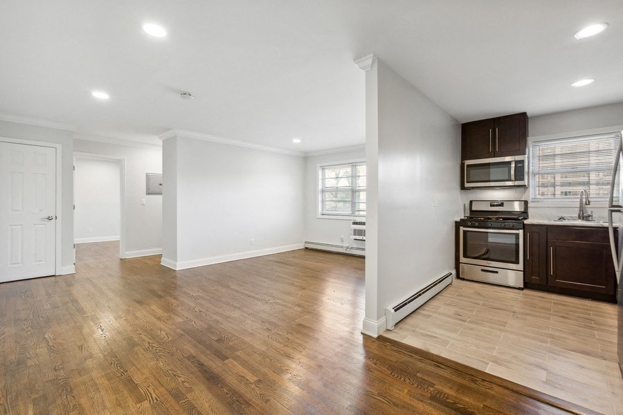 an empty kitchen and living room with wood floors and white walls