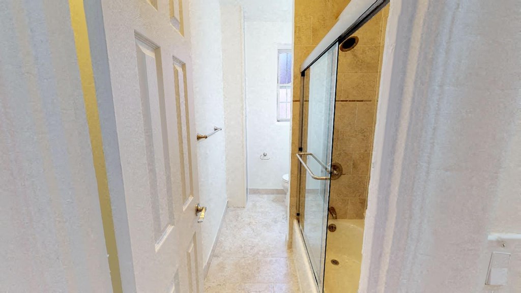 a hallway with a glass door to a bathroom