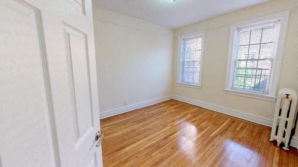 an empty room with a wooden floor and two windows