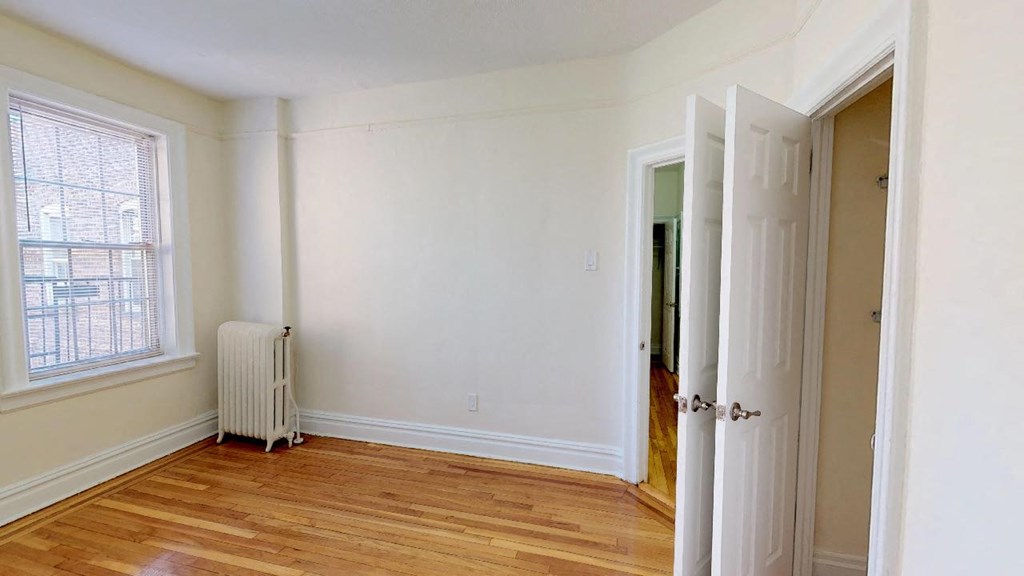 an empty room with white walls and a radiator and a window