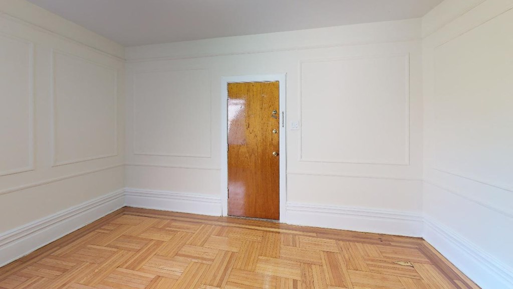 an empty room with a wooden floor and a wooden door