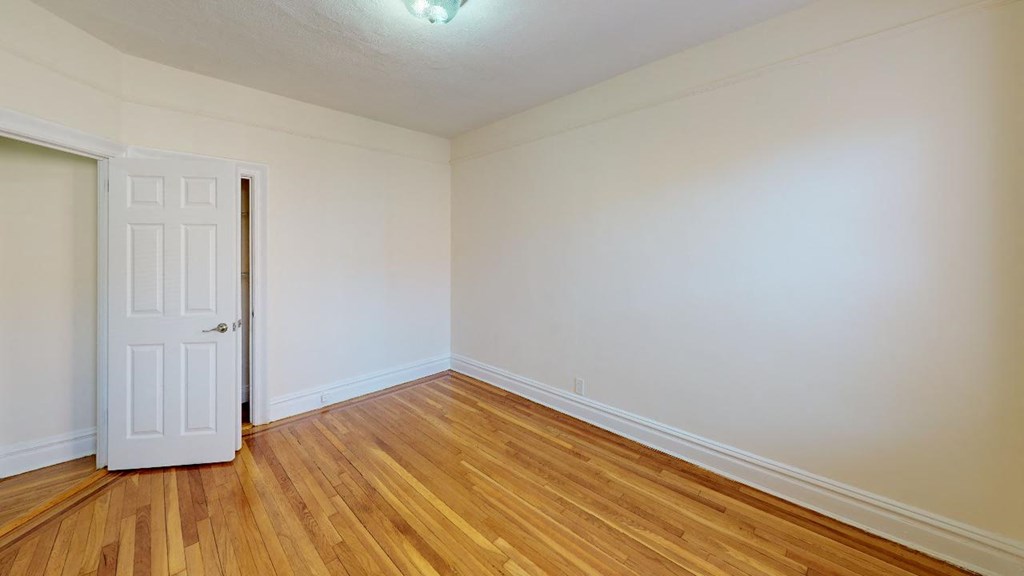 a bedroom with a white door and wood floors