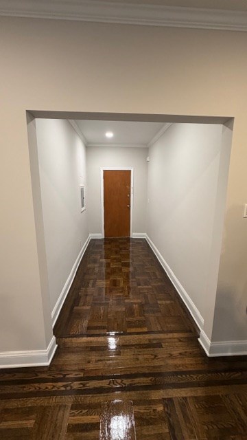 A hallway with a wooden floor and a brown door.