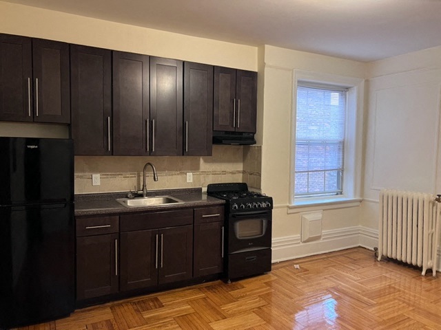 a kitchen with black appliances and wooden floors