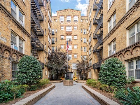 the courtyard of an apartment building with a brick walkway and a flag
