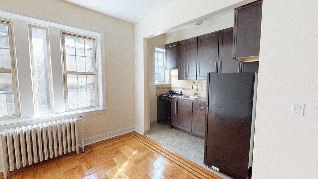 an empty kitchen with a refrigerator and a window