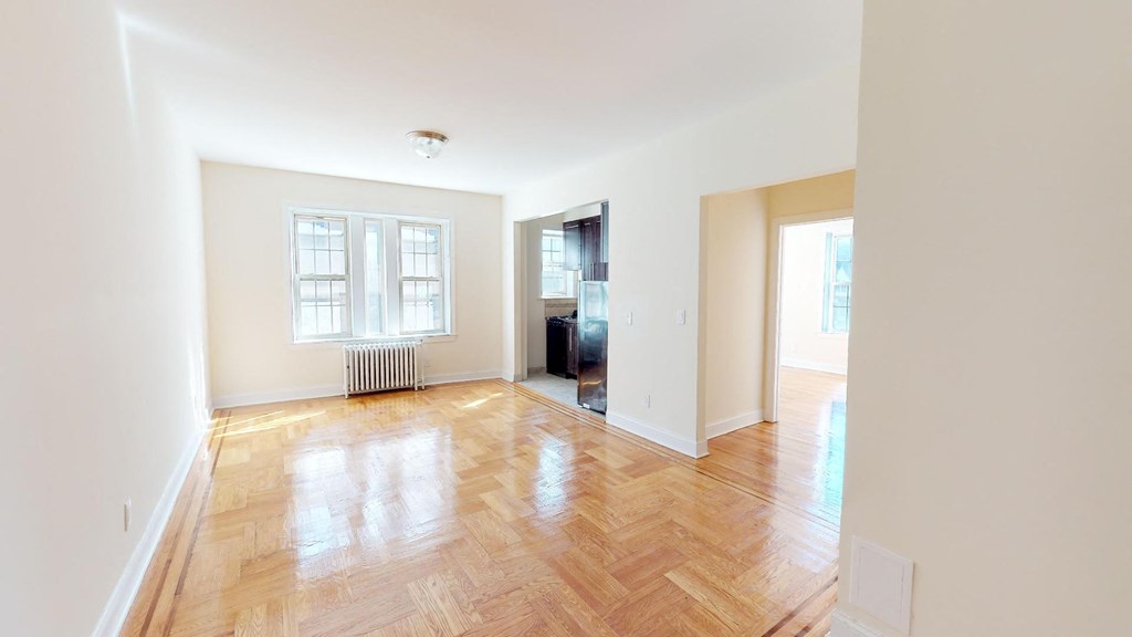 an empty living room with wood floors and a window