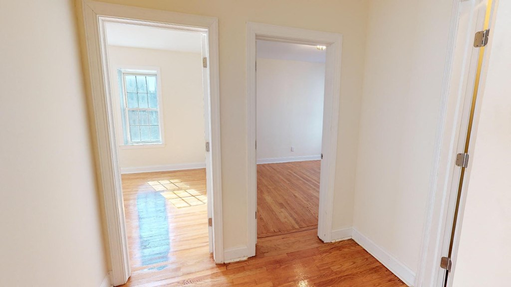 a living room with a hard wood floor and a doorway to a bedroom