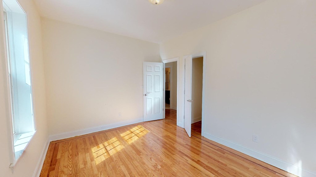 a bedroom with a hard wood floor and a door to a hallway