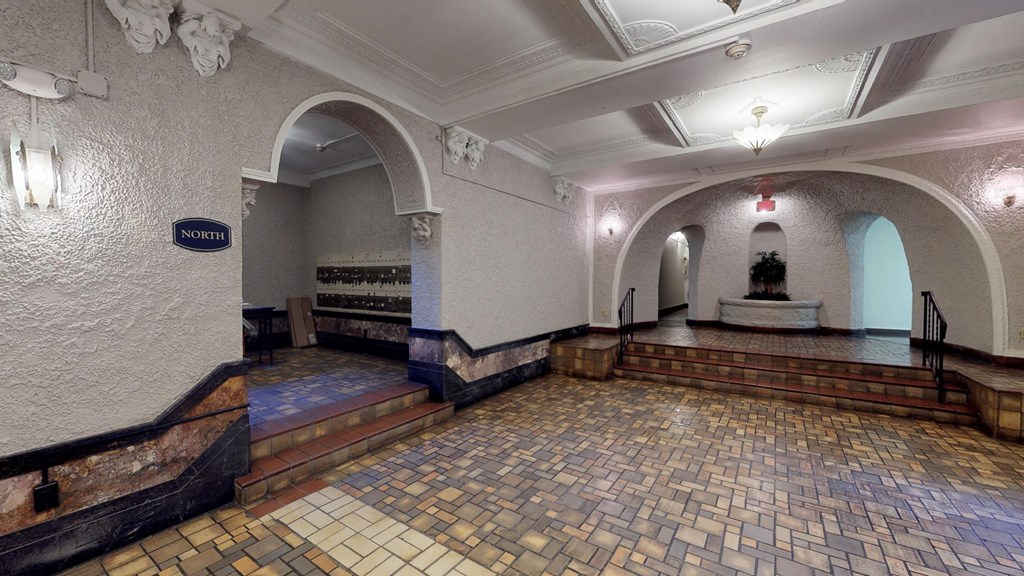 the lobby of a building with a brick floor and white walls