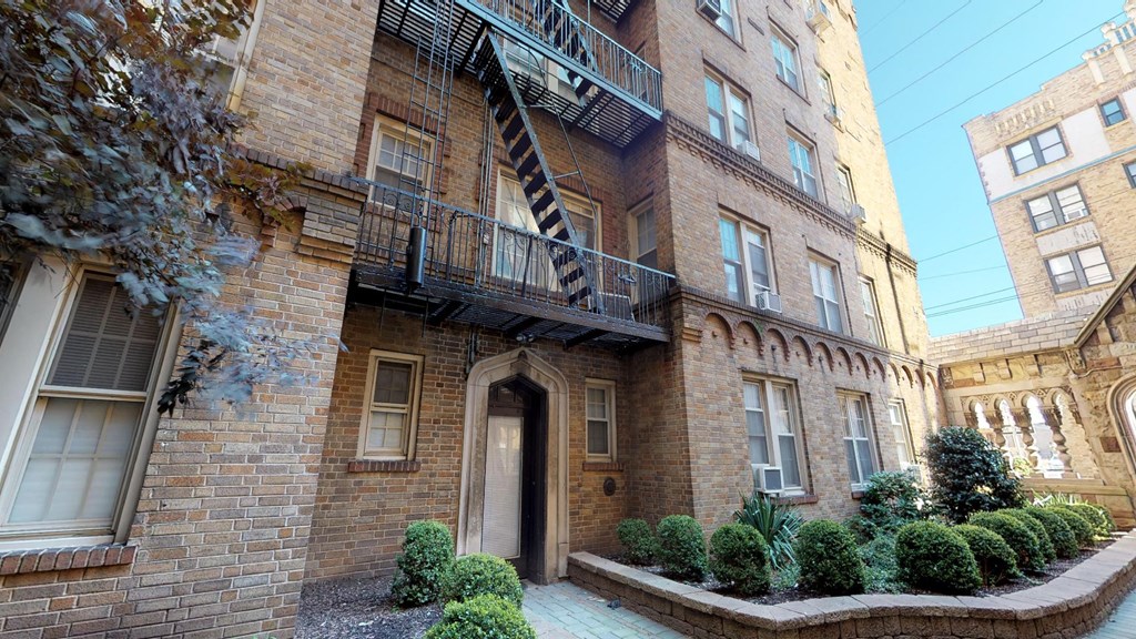 the apartment is in a brick building with a balcony