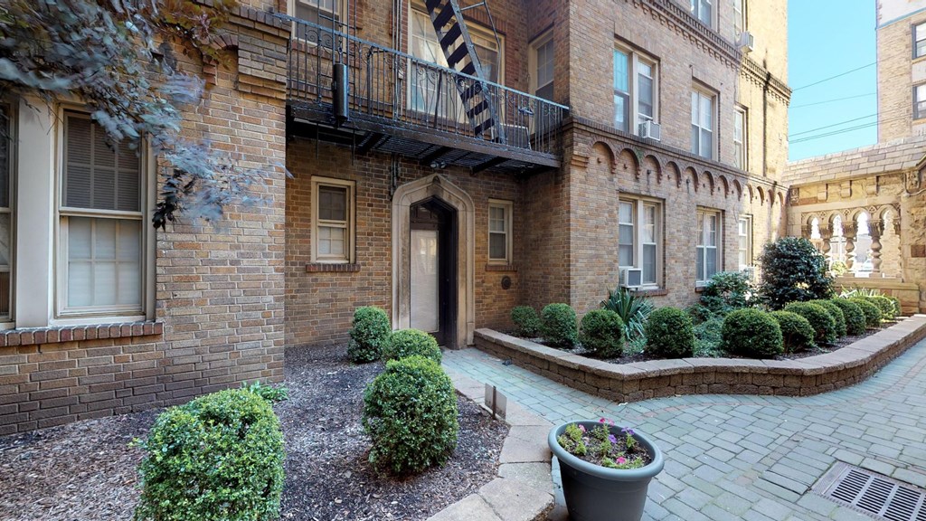the front yard of a brick apartment building with a walkway and plants