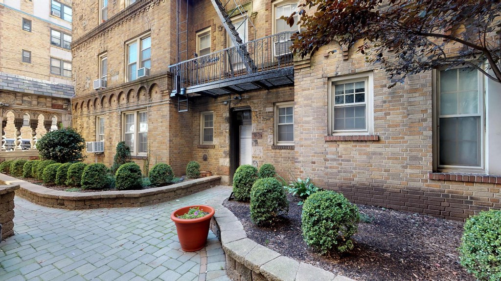 the front yard of a brick apartment building with a patio and plants