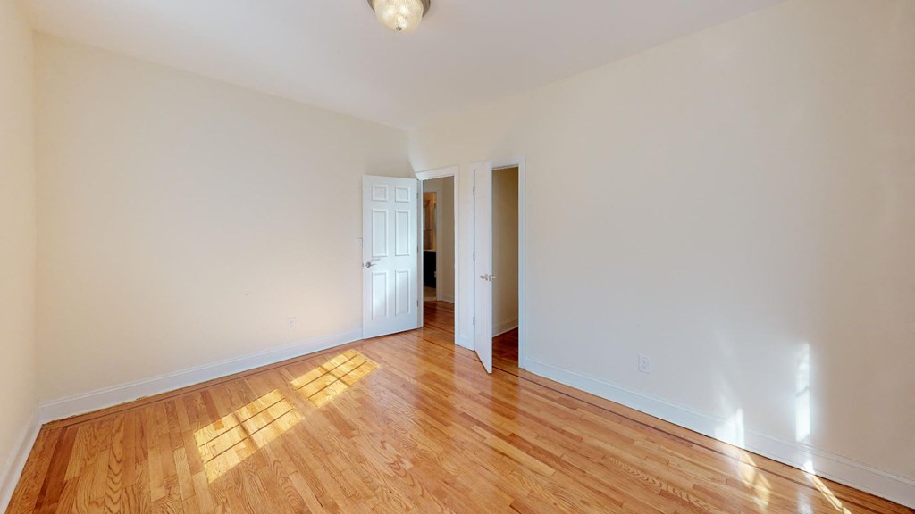 a living room with a hard wood floor and a door into a hallway