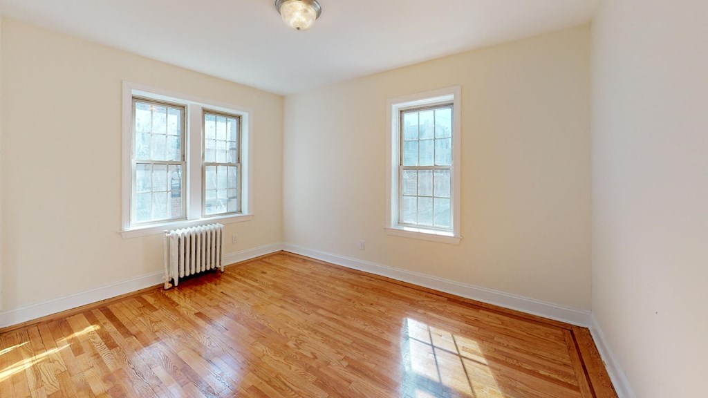 an empty living room with wood floors and two windows