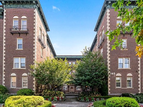 the courtyard of a brick building with trees and bushes