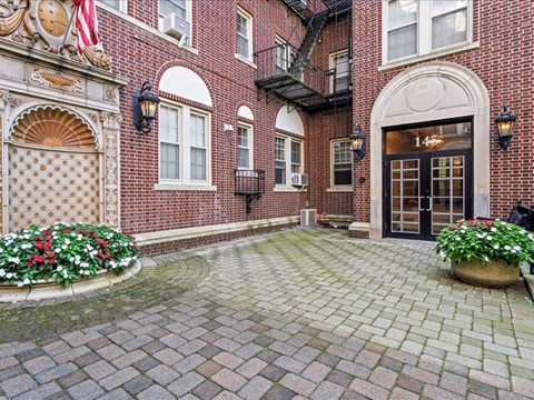 the front door of a brick building with a cobblestone driveway