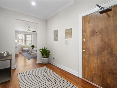 a living room with a wooden door and a black and white rug