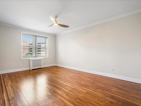 an empty living room with wood floors and a ceiling fan