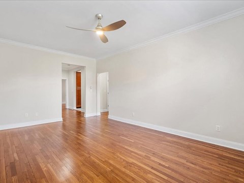 an empty living room with wood floors and a ceiling fan