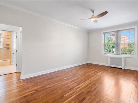 an empty living room with wood floors and a ceiling fan
