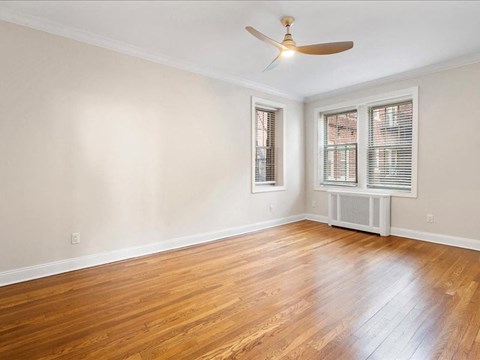 an empty living room with wood floors and a ceiling fan
