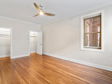 an empty living room with a window and a ceiling fan