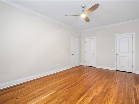 an empty living room with wood floors and a ceiling fan
