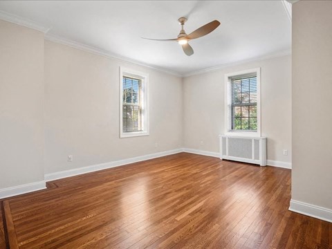 an empty living room with wood floors and a ceiling fan
