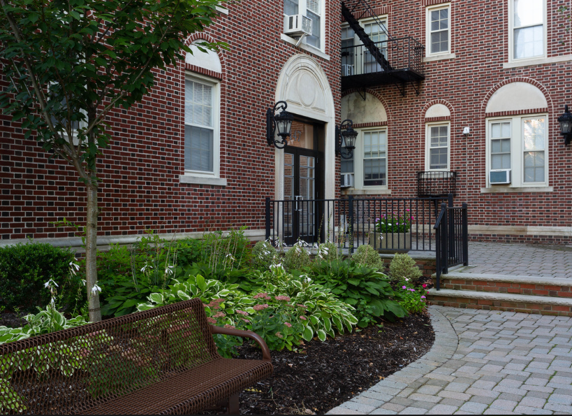 a bench in a garden in front of a brick building